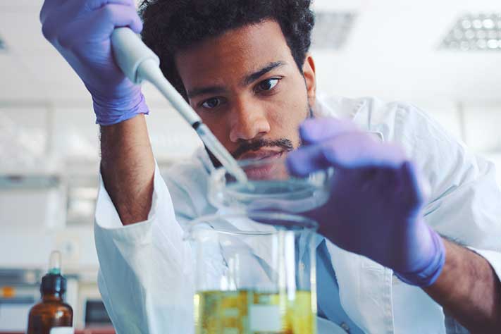 man working with petri dish in lab coat and gloves