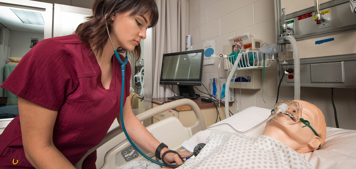 Nursing Student Practicing taking blood pressure on medical mannequin