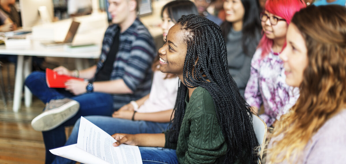 Black female student sitting with classmates listening to a lecture.