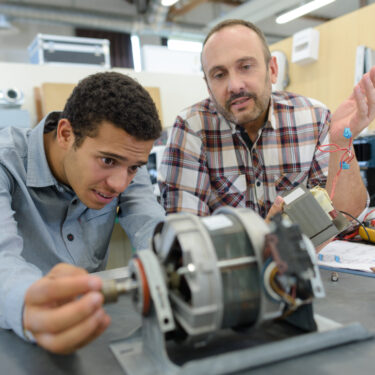Mechanical Engineering students works on a small machine with instructor