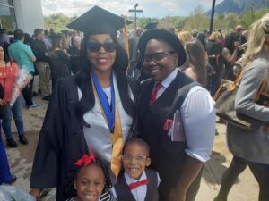 Photo of female student graduating with another young person and two young children