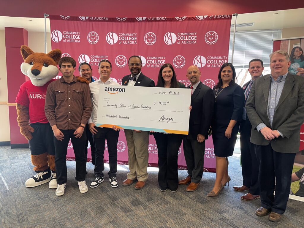 Group receiving an oversized check at Community College of Aurora with the CCA mascot and administrative officials