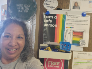 Monica Martinez stands in front of her office door, plastered with colorful signs. 