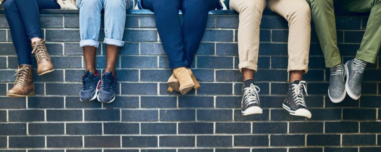 Students' feet hanging over a wall as they relax
