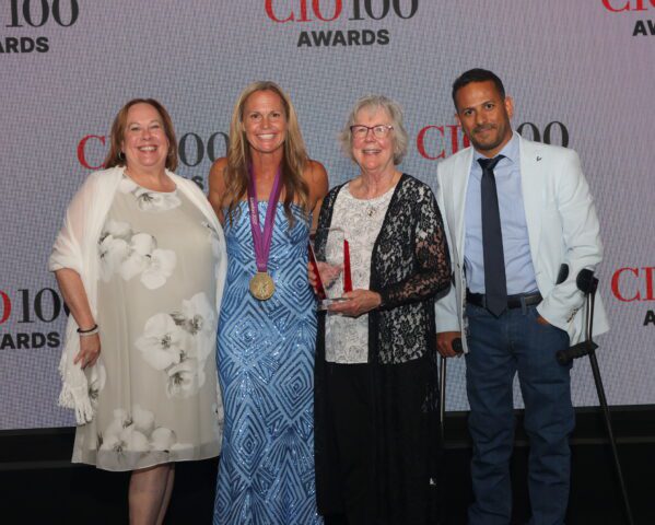 Four individuals at the CIO 100 Award ceremony with one individual holding their award.